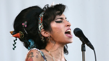 Die britische Sängerin Amy Winehouse singt während eines Auftritts.  | Bild: BR